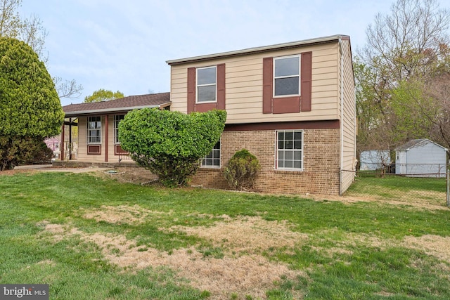 rear view of house featuring brick siding, fence, and a lawn