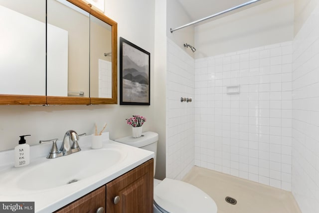 bathroom featuring toilet, tiled shower, and vanity
