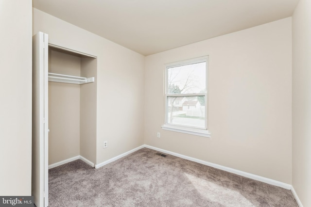 unfurnished bedroom featuring carpet floors, baseboards, a closet, and visible vents