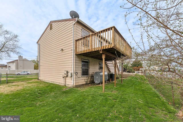 back of property with a yard, a wooden deck, heating fuel, and fence