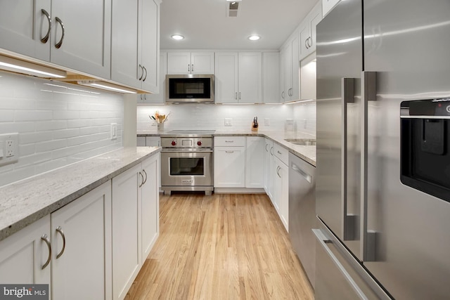 624 4th Pl SW, Washington, DC 20024 - kitchen with stainless steel appliances, white cabinetry, decorative backsplash, light wood-style floors, and recessed lighting