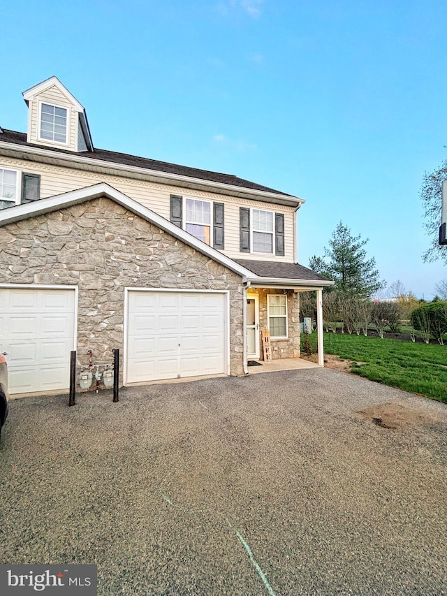 view of front of house featuring covered porch, a garage, driveway, and stone siding