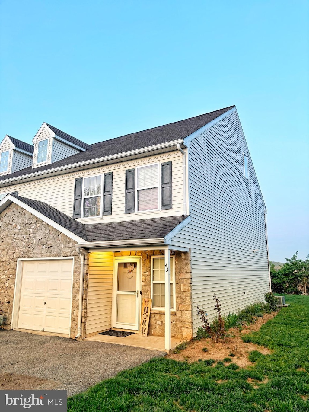 traditional-style home featuring stone siding, a shingled roof, and a garage