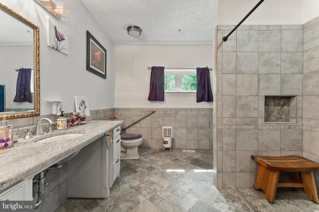 6707 Burch Hill Rd, Brandywine, MD 20613 - bathroom featuring tiled shower, toilet, vanity, a textured ceiling, and tile walls