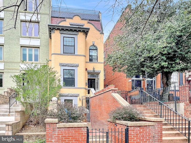 view of front of home with fence, stairway, and brick siding