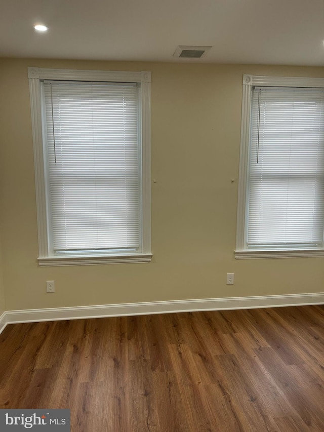 unfurnished room with visible vents, wood finished floors, and baseboards