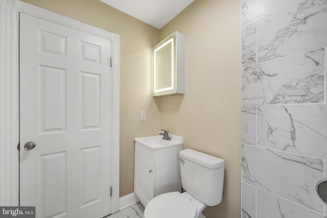 bathroom featuring baseboards, toilet, vanity, and marble finish floor