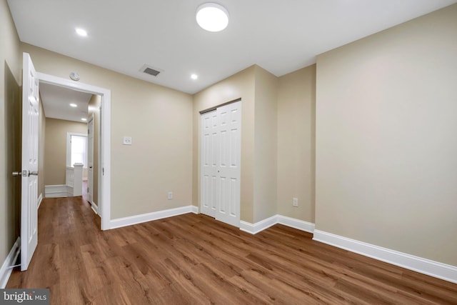 unfurnished bedroom with recessed lighting, wood finished floors, a closet, baseboards, and visible vents