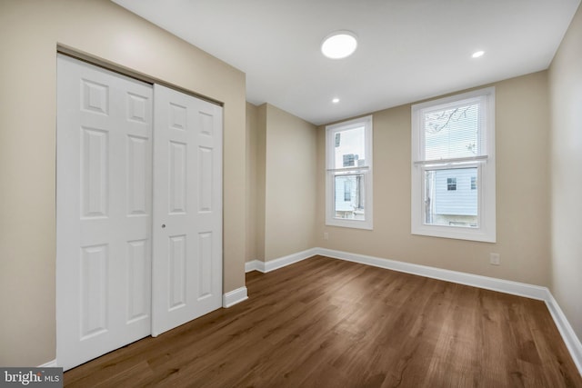 unfurnished bedroom featuring dark wood-style floors, a closet, recessed lighting, and baseboards