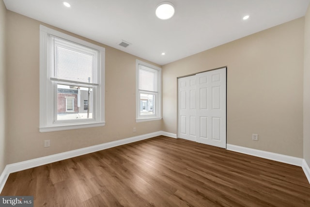 unfurnished bedroom with recessed lighting, wood finished floors, a closet, baseboards, and visible vents