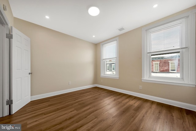 spare room featuring wood finished floors, visible vents, and baseboards