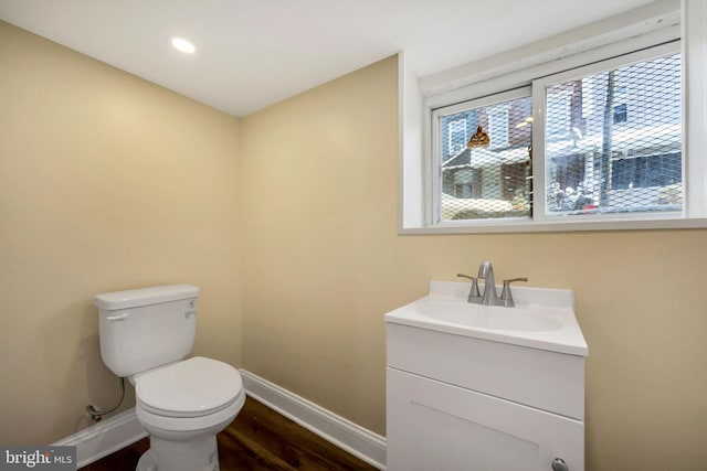 half bath featuring recessed lighting, vanity, toilet, baseboards, and wood finished floors
