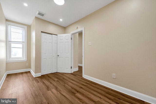 unfurnished bedroom featuring recessed lighting, a closet, visible vents, baseboards, and wood finished floors