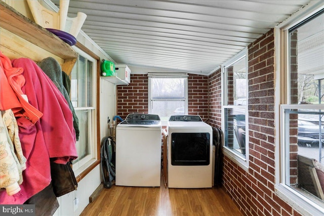washroom with independent washer and dryer, laundry area, wood finished floors, and brick wall
