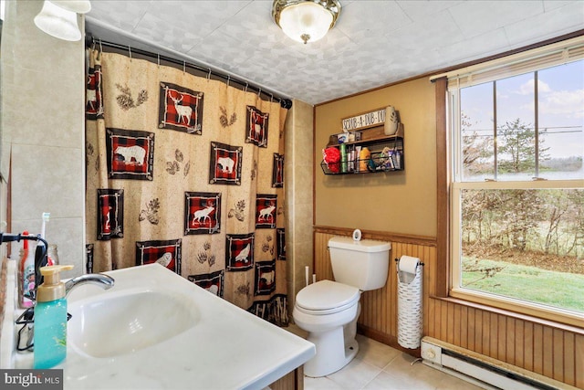bathroom featuring tile patterned floors, toilet, a baseboard heating unit, and a healthy amount of sunlight