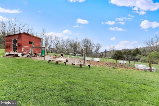 view of property's community featuring fence, an outdoor structure, and a lawn