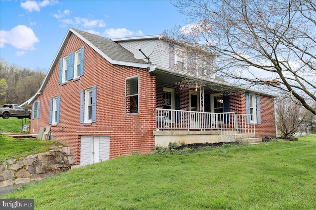 traditional-style home with covered porch, a front yard, a garage, and brick siding
