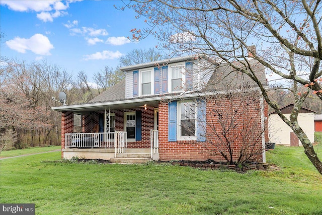 view of front of property with a shingled roof, brick siding, a front lawn, and covered porch