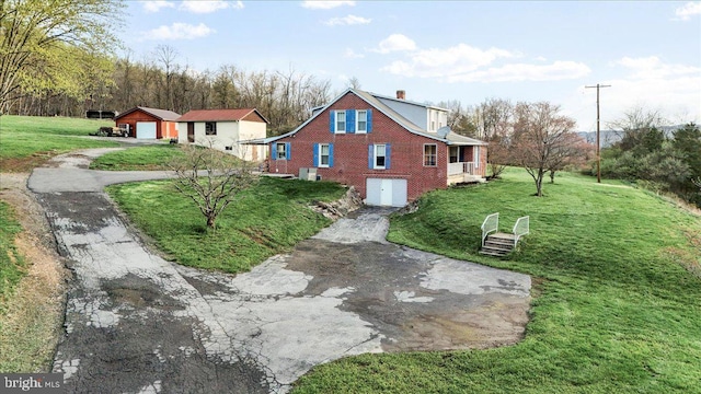exterior space featuring a chimney, driveway, an outdoor structure, and a lawn
