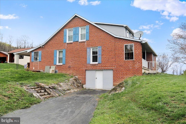 back of house featuring a yard, brick siding, and driveway