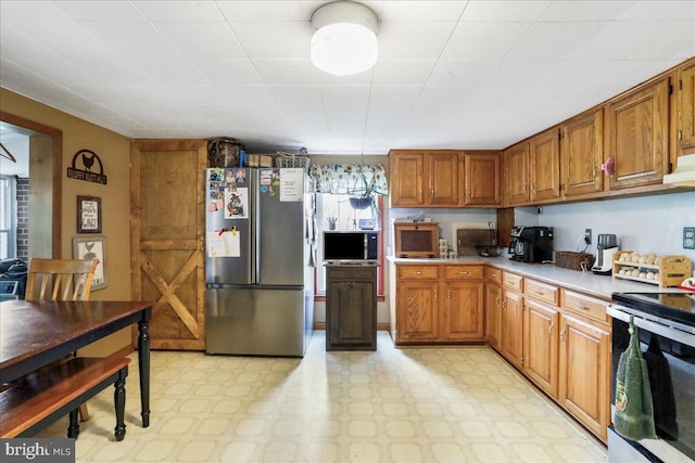 kitchen with stainless steel appliances, brown cabinets, light countertops, and light floors