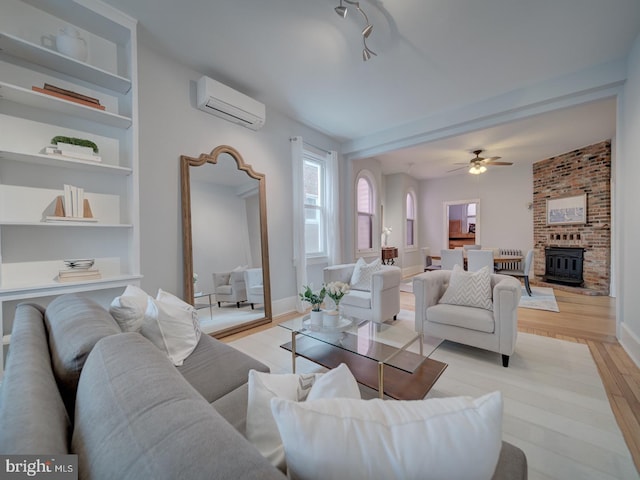 1234 Monroe St NE, Washington, DC 20017 - living room featuring baseboards, built in shelves, a wall mounted air conditioner, ceiling fan, and light wood finished floors