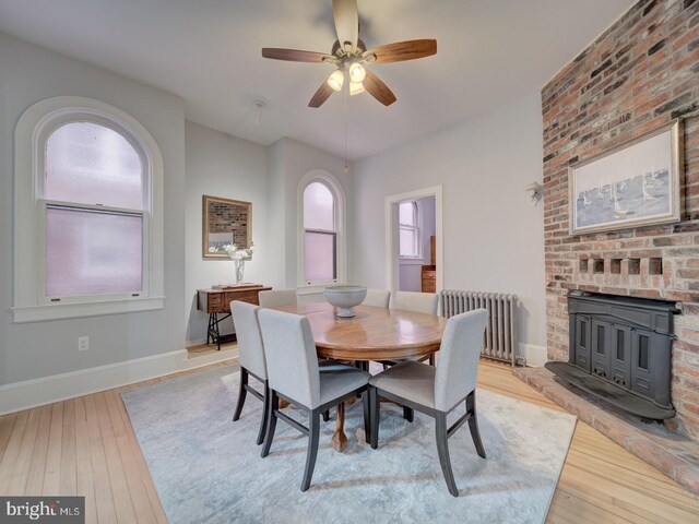 1234 Monroe St NE, Washington, DC 20017 - dining space with a wood stove, light wood-style flooring, radiator heating unit, a ceiling fan, and baseboards
