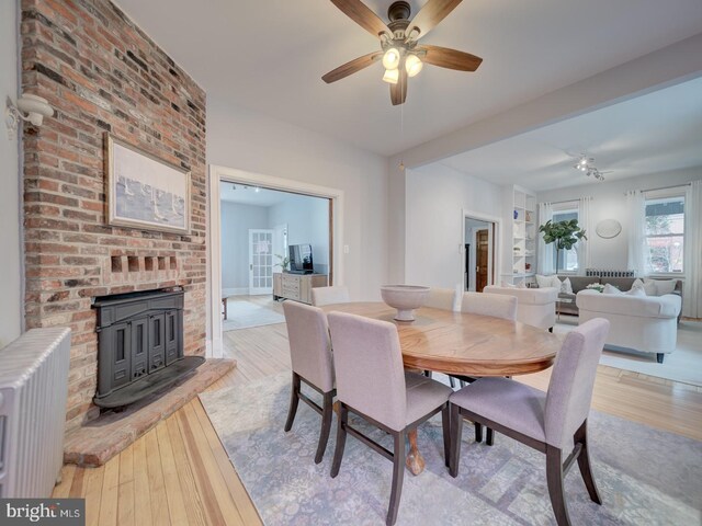 1234 Monroe St NE, Washington, DC 20017 - dining area with baseboards, radiator heating unit, a wood stove, ceiling fan, and wood finished floors