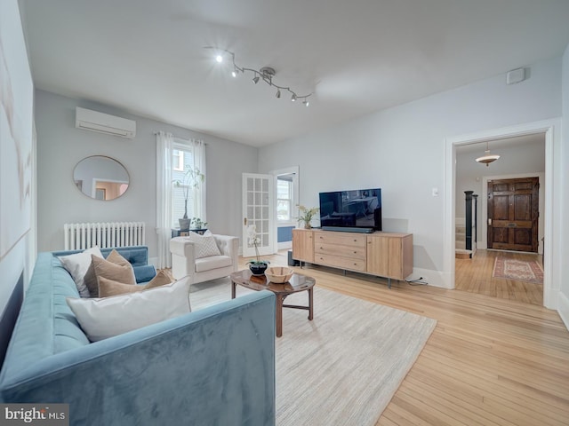 1234 Monroe St NE, Washington, DC 20017 - living area featuring light wood-type flooring, baseboards, a wall mounted air conditioner, rail lighting, and radiator heating unit