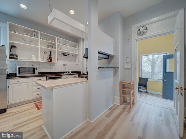 1234 Monroe St NE, Washington, DC 20017 - kitchen with baseboards, light wood-style floors, white cabinetry, stainless steel appliances, and backsplash
