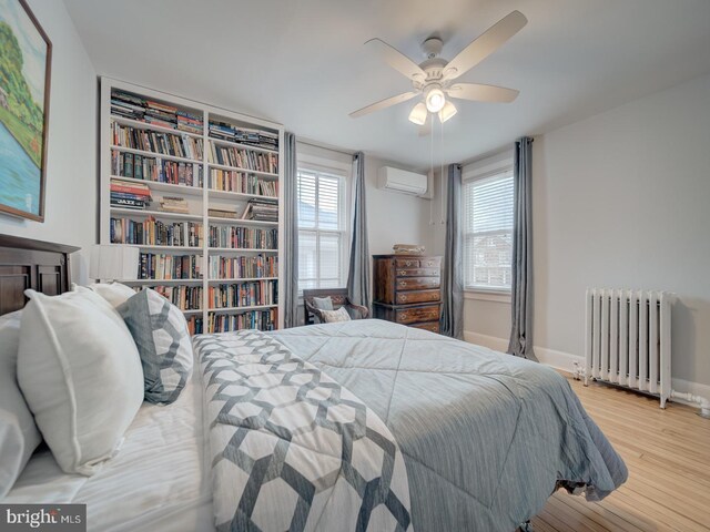 1234 Monroe St NE, Washington, DC 20017 - bedroom with radiator heating unit, multiple windows, a wall mounted air conditioner, and wood finished floors