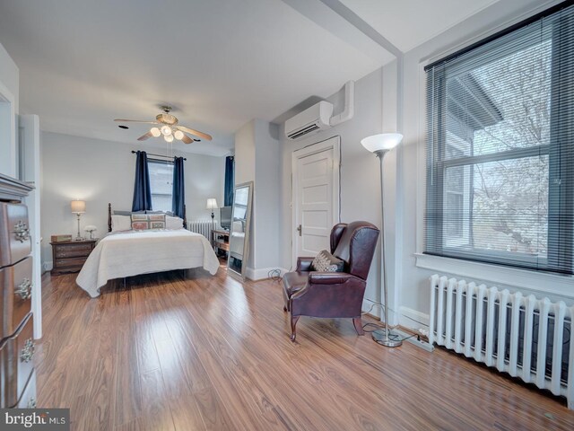 1234 Monroe St NE, Washington, DC 20017 - bedroom featuring radiator heating unit, baseboards, a wall mounted air conditioner, and wood finished floors