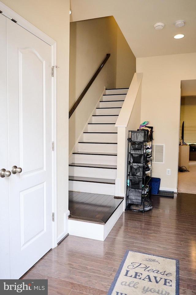 stairway featuring wood finished floors, baseboards, and visible vents