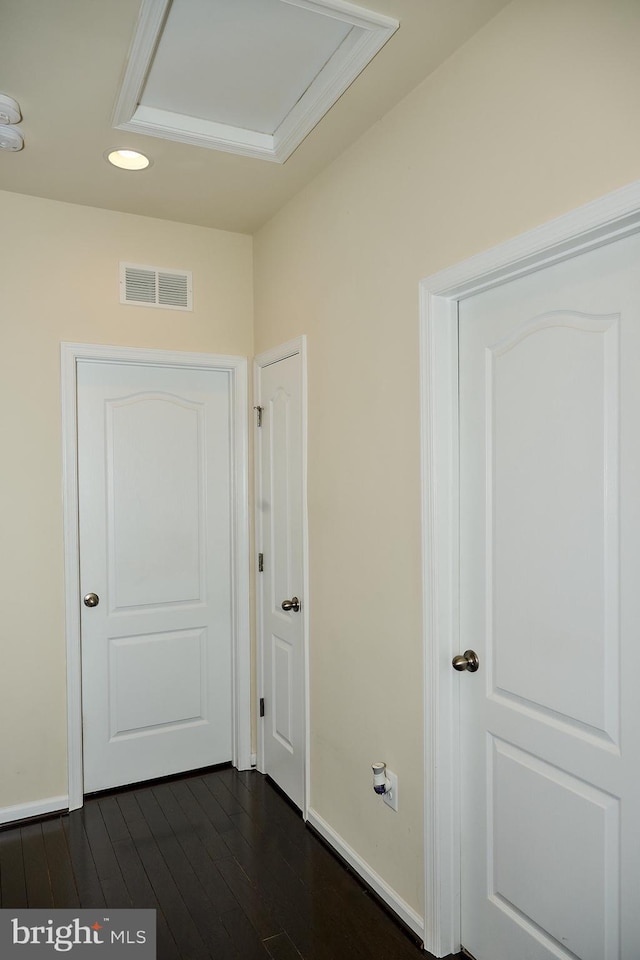 hall with visible vents, baseboards, and dark wood finished floors