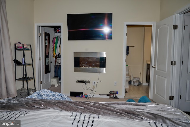 bedroom featuring a closet, a spacious closet, ensuite bathroom, and tile patterned floors