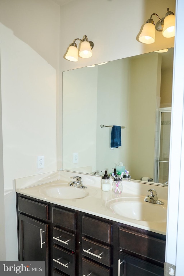 full bathroom with a sink, double vanity, and a shower with door