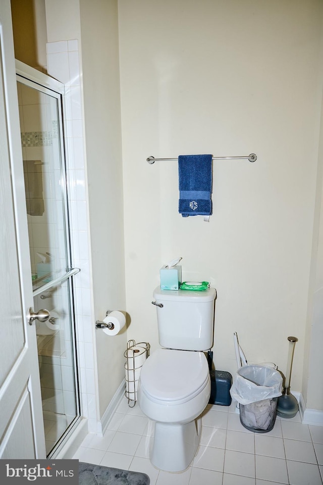 bathroom featuring toilet, tile patterned floors, a stall shower, and baseboards