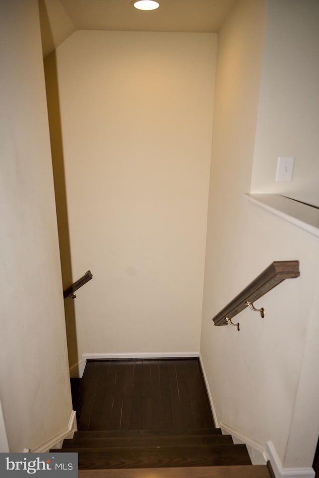 staircase featuring baseboards and wood finished floors