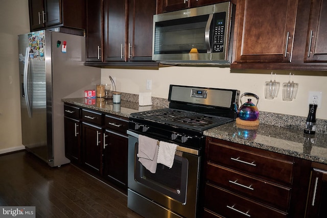 kitchen featuring dark stone countertops, appliances with stainless steel finishes, dark brown cabinetry, and dark wood-type flooring