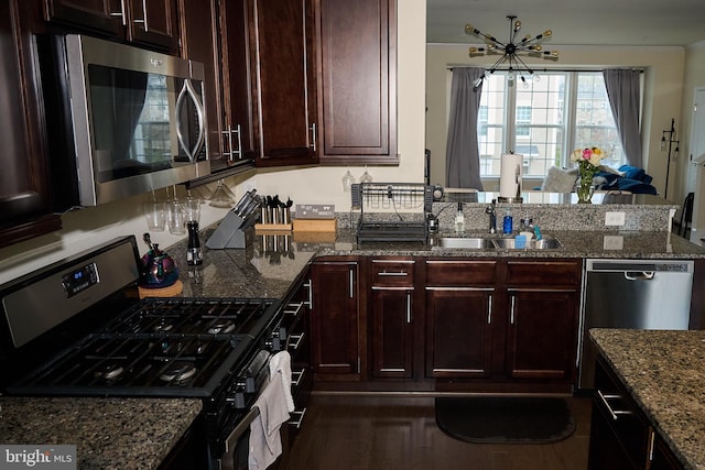 kitchen with a peninsula, dark stone counters, an inviting chandelier, and stainless steel appliances
