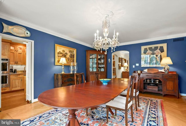 dining space featuring visible vents, crown molding, baseboards, a chandelier, and arched walkways
