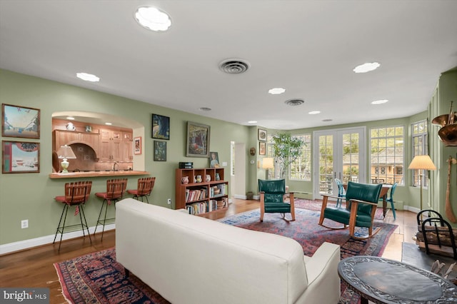 living area featuring recessed lighting, arched walkways, baseboards, and visible vents