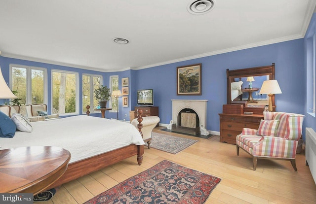 bedroom with crown molding, visible vents, hardwood / wood-style flooring, and a fireplace