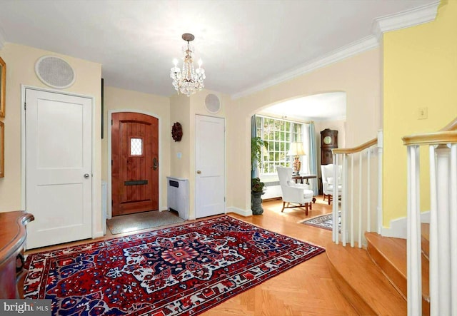 entryway featuring crown molding, arched walkways, a chandelier, and stairway