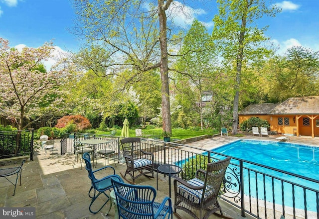 view of pool featuring a fenced in pool, an outdoor structure, a diving board, and a patio area