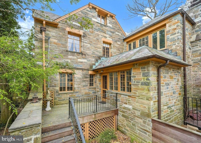 rear view of house with a wooden deck and stone siding