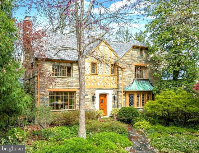 english style home with a chimney and stone siding