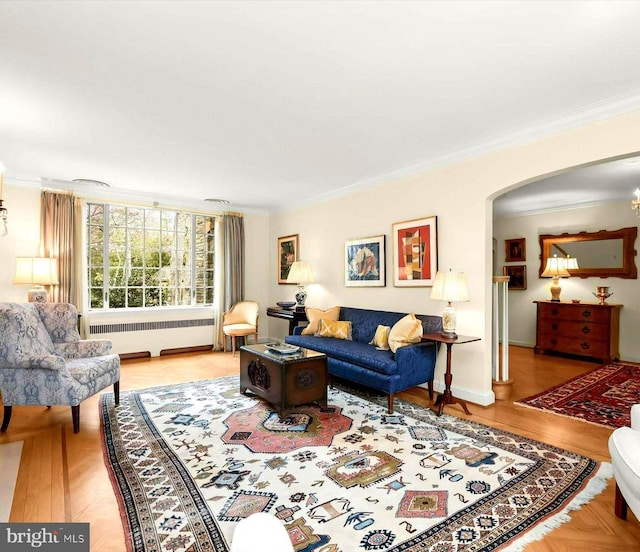 living area featuring radiator heating unit, arched walkways, ornamental molding, and wood finished floors
