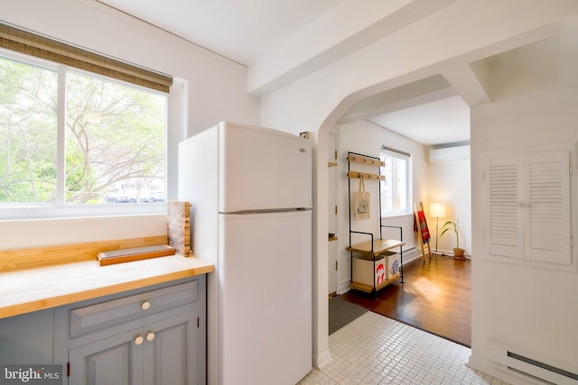 27 Ridge Rd, Greenbelt, MD 20770 - kitchen with a wall mounted AC, a baseboard heating unit, freestanding refrigerator, gray cabinetry, and arched walkways
