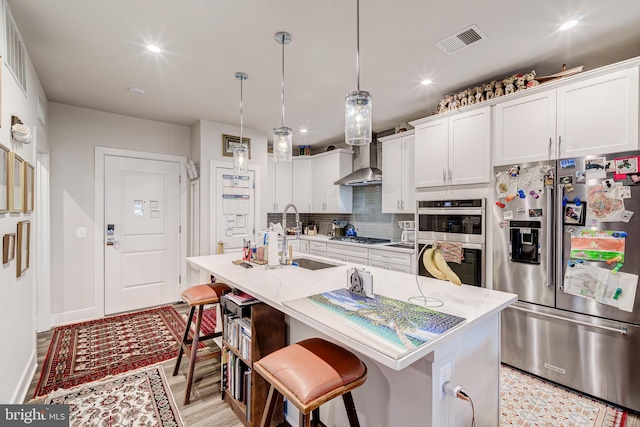 104 Saint Ives Pl Unit 409, Oxon Hill, MD 20745 - kitchen with tasteful backsplash, visible vents, a sink, wall chimney range hood, and stainless steel appliances